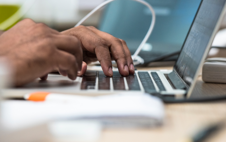Image showing a mans pair of hands typing on a laptop keyboard